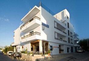Un edificio moderno blanco con balcones, un cartel que dice "CAN JURAT" y una entrada visible.