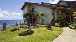A building with a view of the ocean, a statue, and a landscaped garden with rocks and plants. - Club Wyndham Shearwater (Princeville)