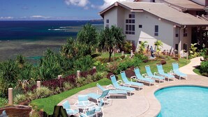 A resort with a pool, lounge chairs, and a view of the ocean. - Club Wyndham Shearwater (Princeville)