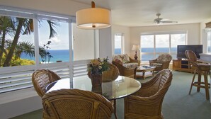 A living room with a glass table, wicker chairs, a sofa, and a TV. - Club Wyndham Shearwater (Princeville)