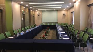 A conference room with a long table, chairs, and a projector screen.