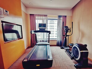 A hotel room with a treadmill, a stationary bike, and a large window with curtains. - Holiday Inn Express Xi'an High-tech Zone by IHG (Xi'an)
