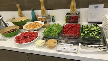 A buffet with various food items including fruits, vegetables, and pasta.