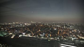 A nighttime cityscape with illuminated buildings and a distant moon.