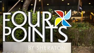 Un letrero de 'FOUR POINTS BY SHERATON' con un logotipo que presenta una 'X' estilizada y una flor.