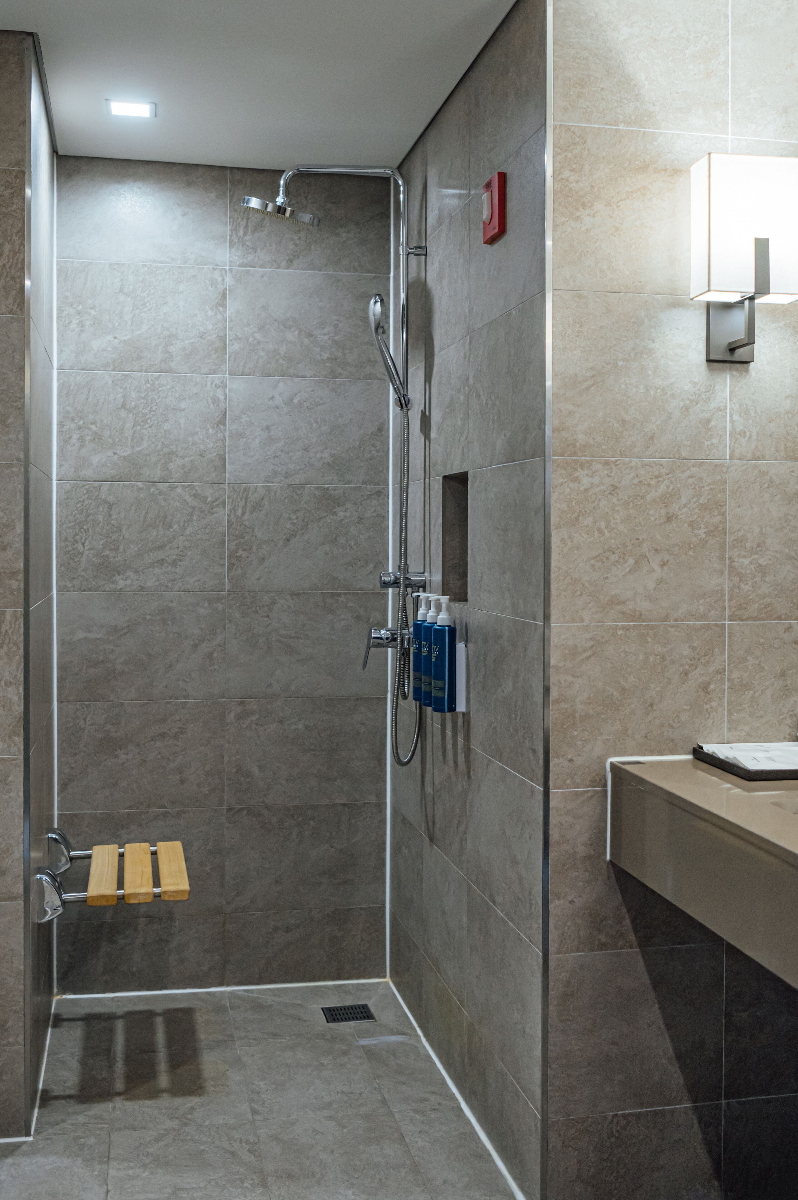 A modern shower area with a glass-enclosed shower, a handheld showerhead, and a handheld faucet.