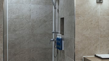 A modern shower area with a glass-enclosed shower, a handheld showerhead, and a handheld faucet.