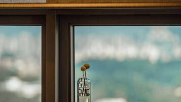 Un comedor con una mesa y sillas, una ventana con vistas al cielo y un florero con una flor sobre la mesa.