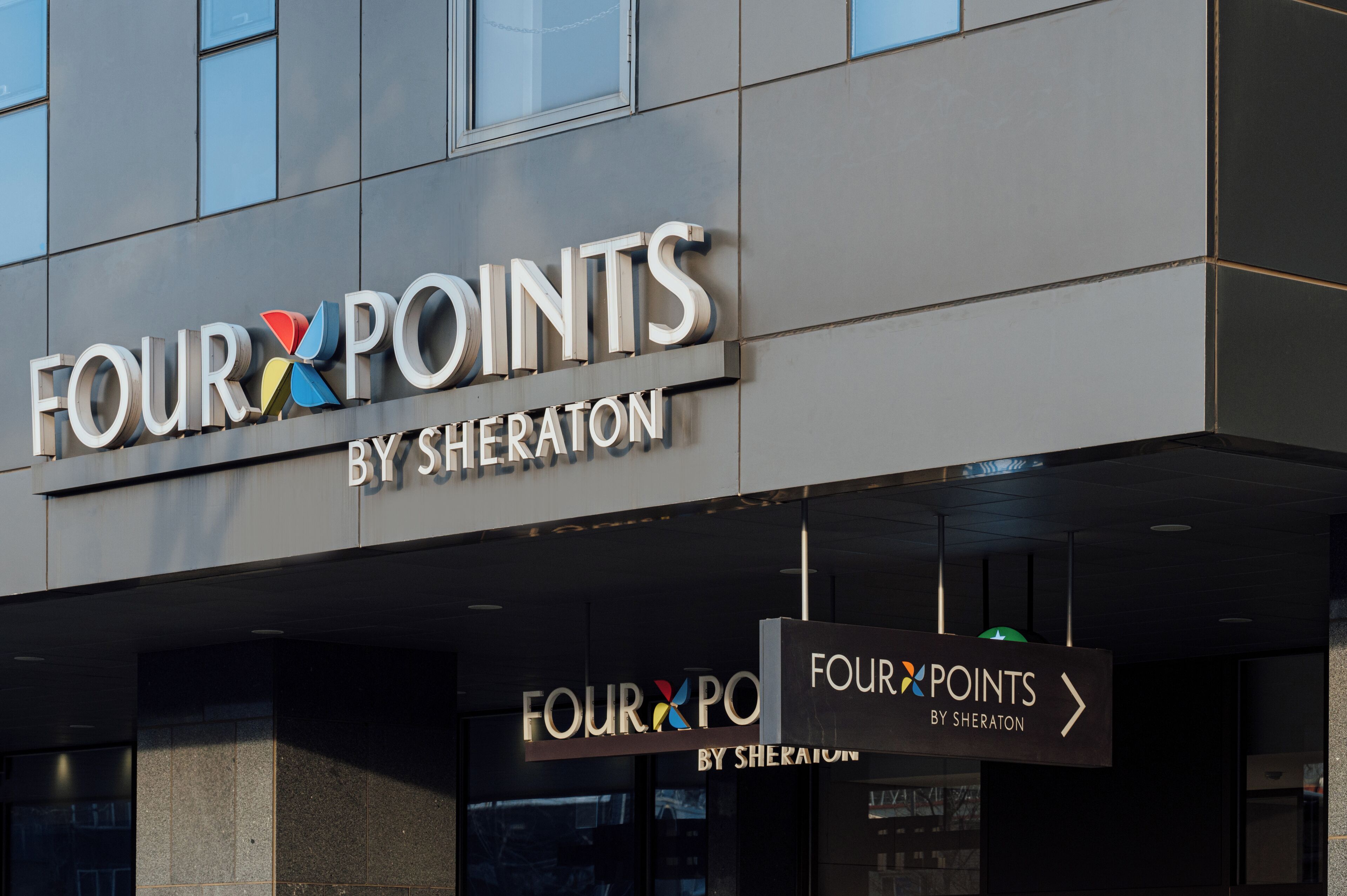 Un cartel de hotel con el nombre "FOUR POINTS BY SHERATON" y flechas que indican la ubicación del hotel.