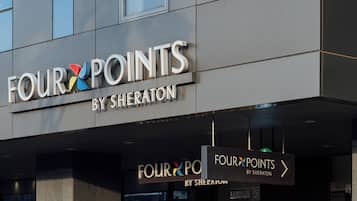 Un cartel de hotel con el nombre "FOUR POINTS BY SHERATON" y flechas que indican la ubicación del hotel.