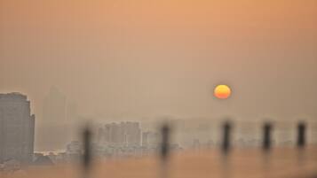 A cityscape with a hazy atmosphere and a visible sun.