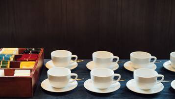 A table with white cups and saucers, arranged neatly on a dark tablecloth.