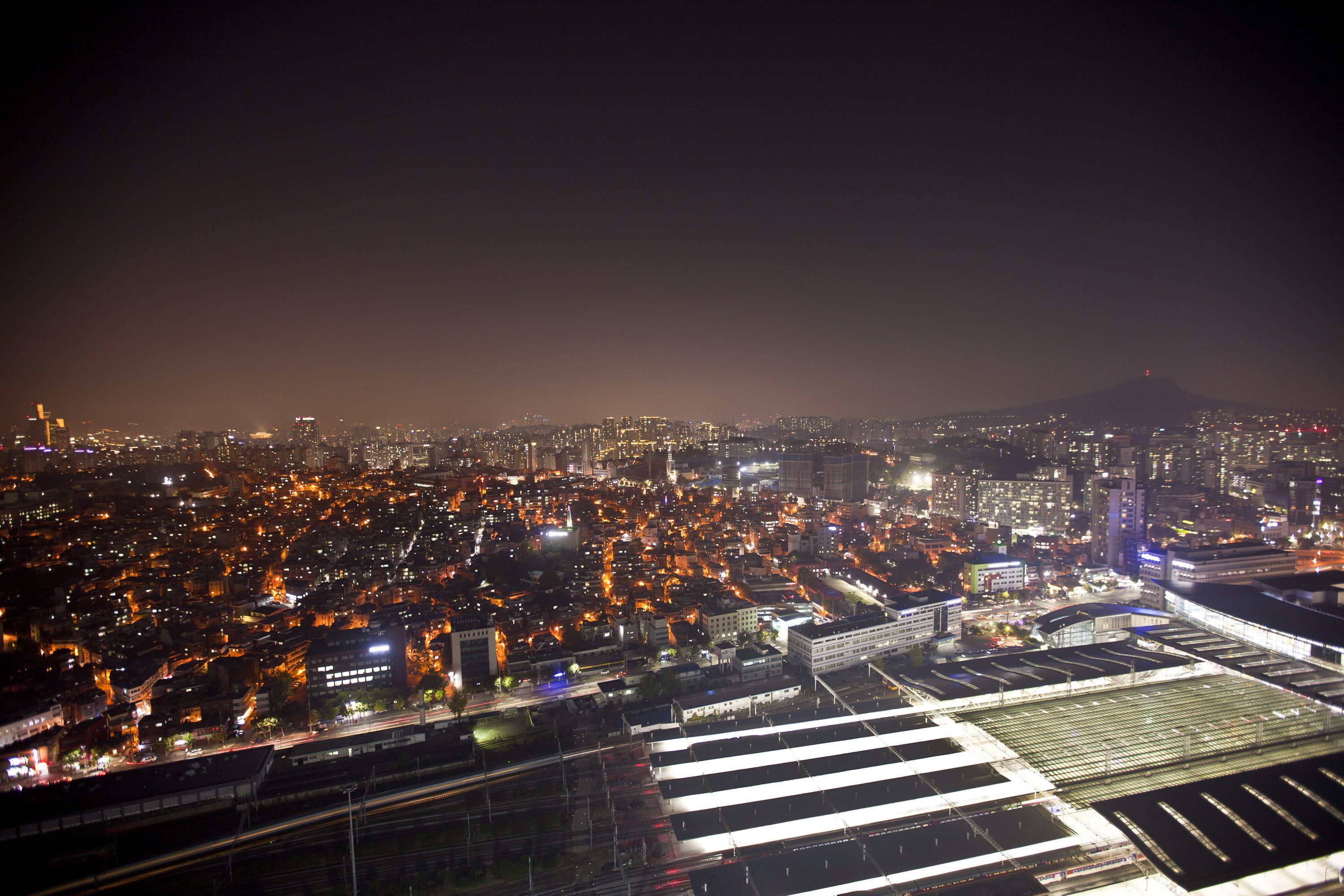 A nighttime cityscape with a prominent mountain in the background.