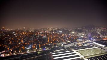 A nighttime cityscape with a prominent mountain in the background.