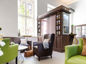 A modern living room with a fireplace, green chairs, a sofa, and a coffee table. - ibis Styles Trier (Trier)