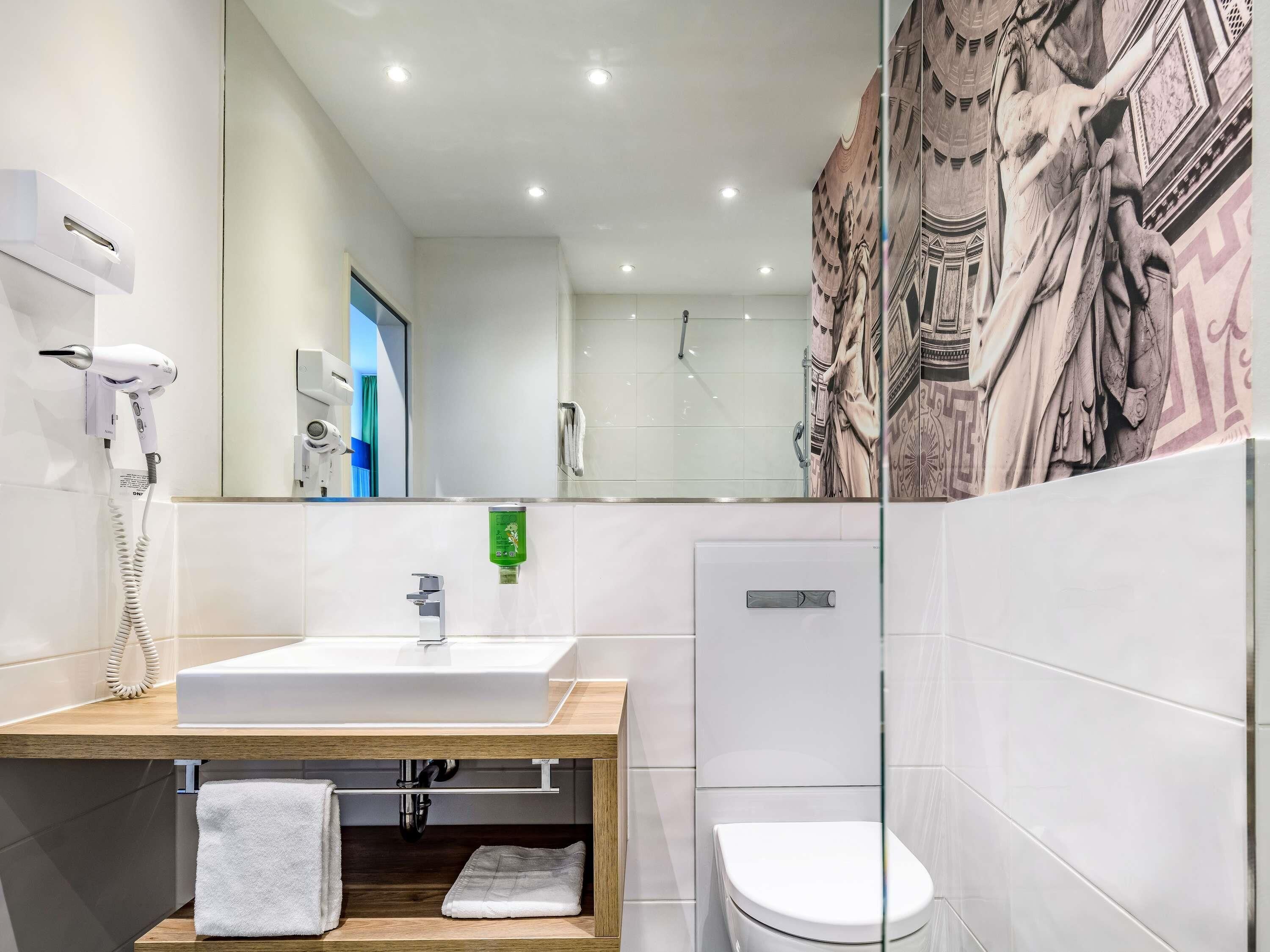 A modern bathroom with a sink, mirror, towel rack, and toilet.