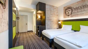 Une chambre d’hôtel avec deux lits, un mur décoratif en briques, une tête de lit verte et une grande œuvre d’art au-dessus du lit.