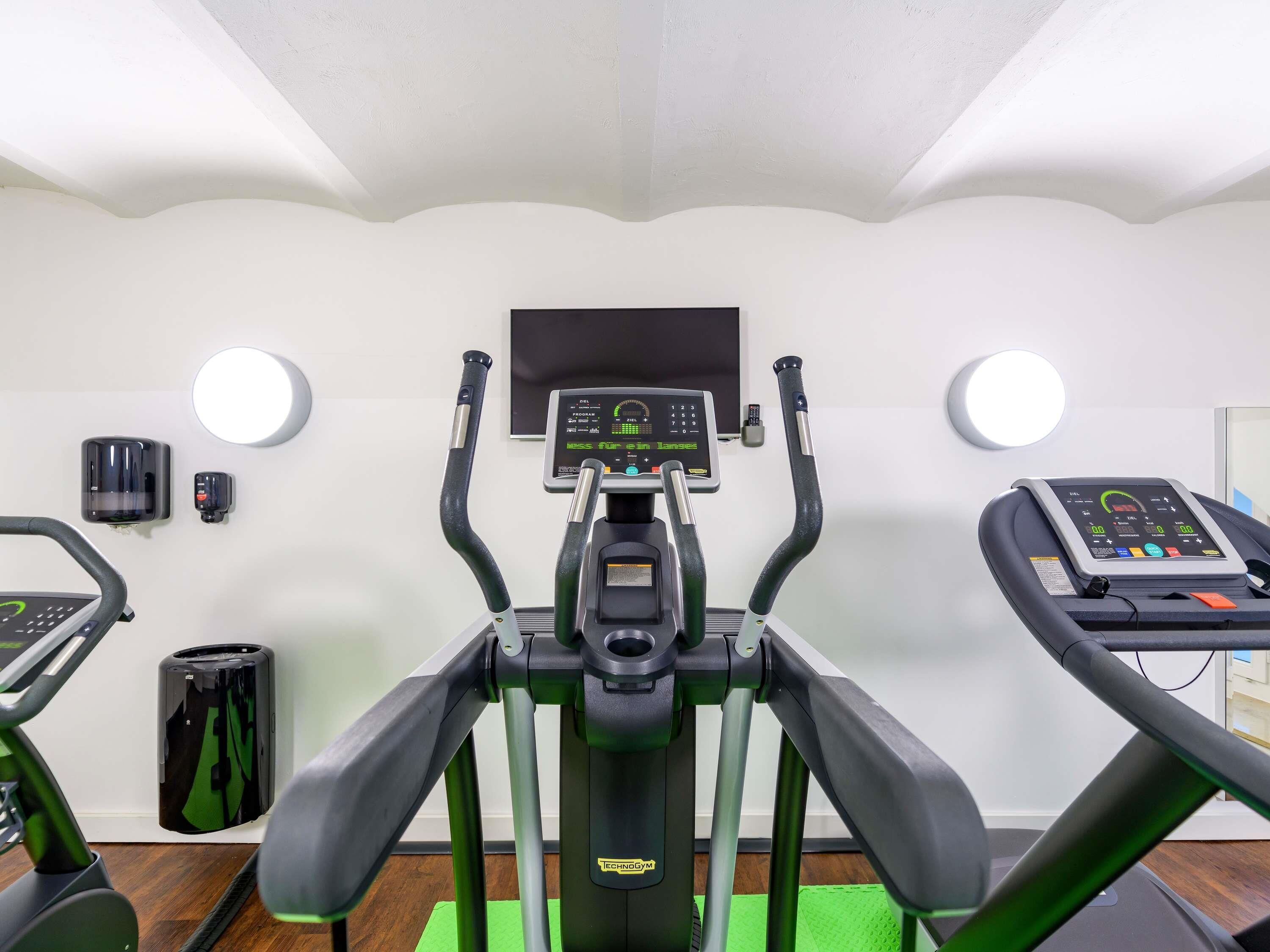 A gym with a treadmill, stationary bikes, and exercise equipment.