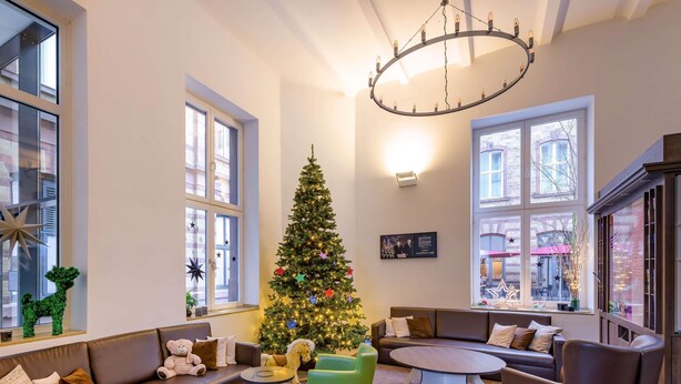 Una sala de estar acogedora con un árbol de Navidad, sofás de cuero, una mesa de centro redonda y ventanas amplias.