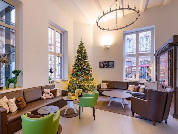 Una sala de estar acogedora con un árbol de Navidad, sofás de cuero, una mesa de centro redonda y ventanas amplias.
