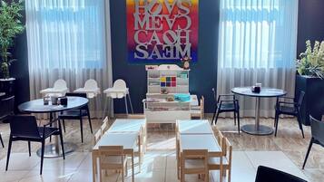 Uma área de recreação infantil com mesas, cadeiras e uma estrutura de jogos colorida.