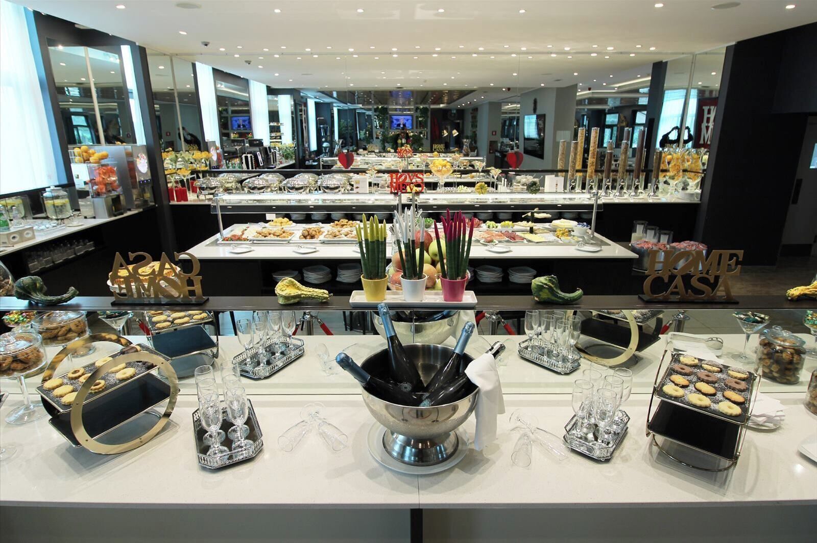 A buffet area with various food items, a champagne bucket, and a 'HOME CAST' sign.