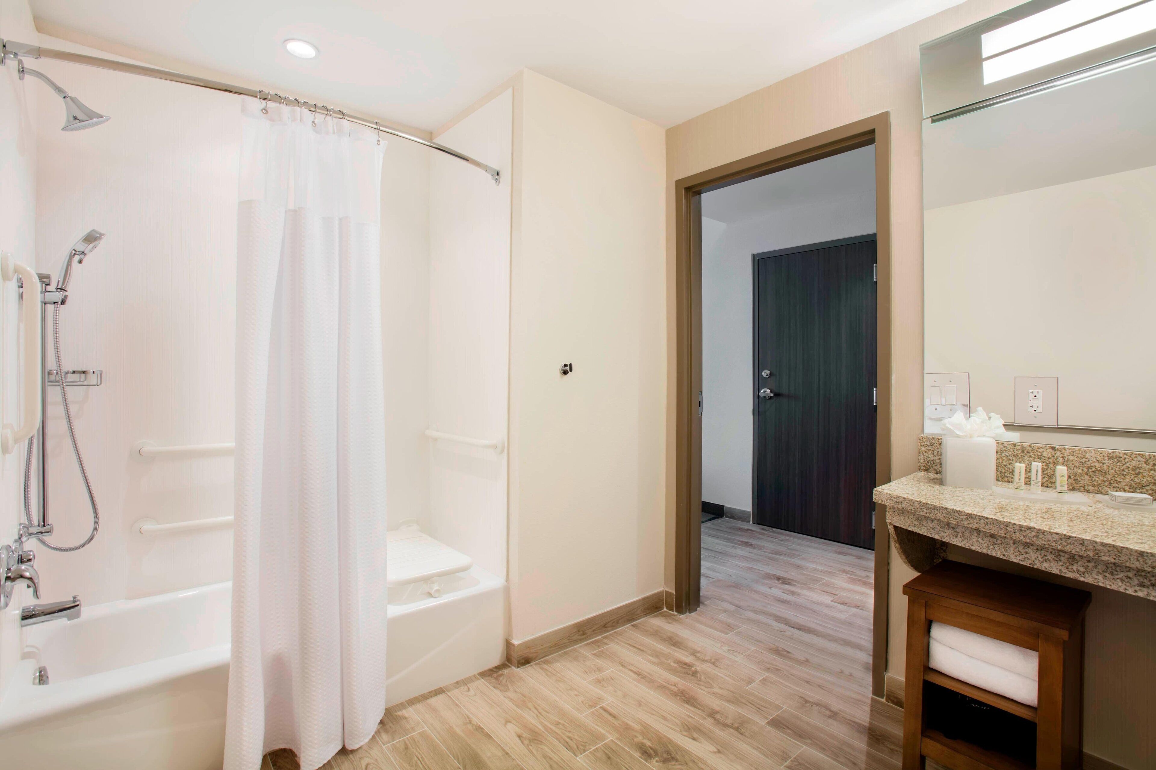 A modern bathroom with a bathtub, shower, and vanity.