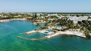 An aerial view of a coastal resort with a marina, palm trees, and a large building complex.
