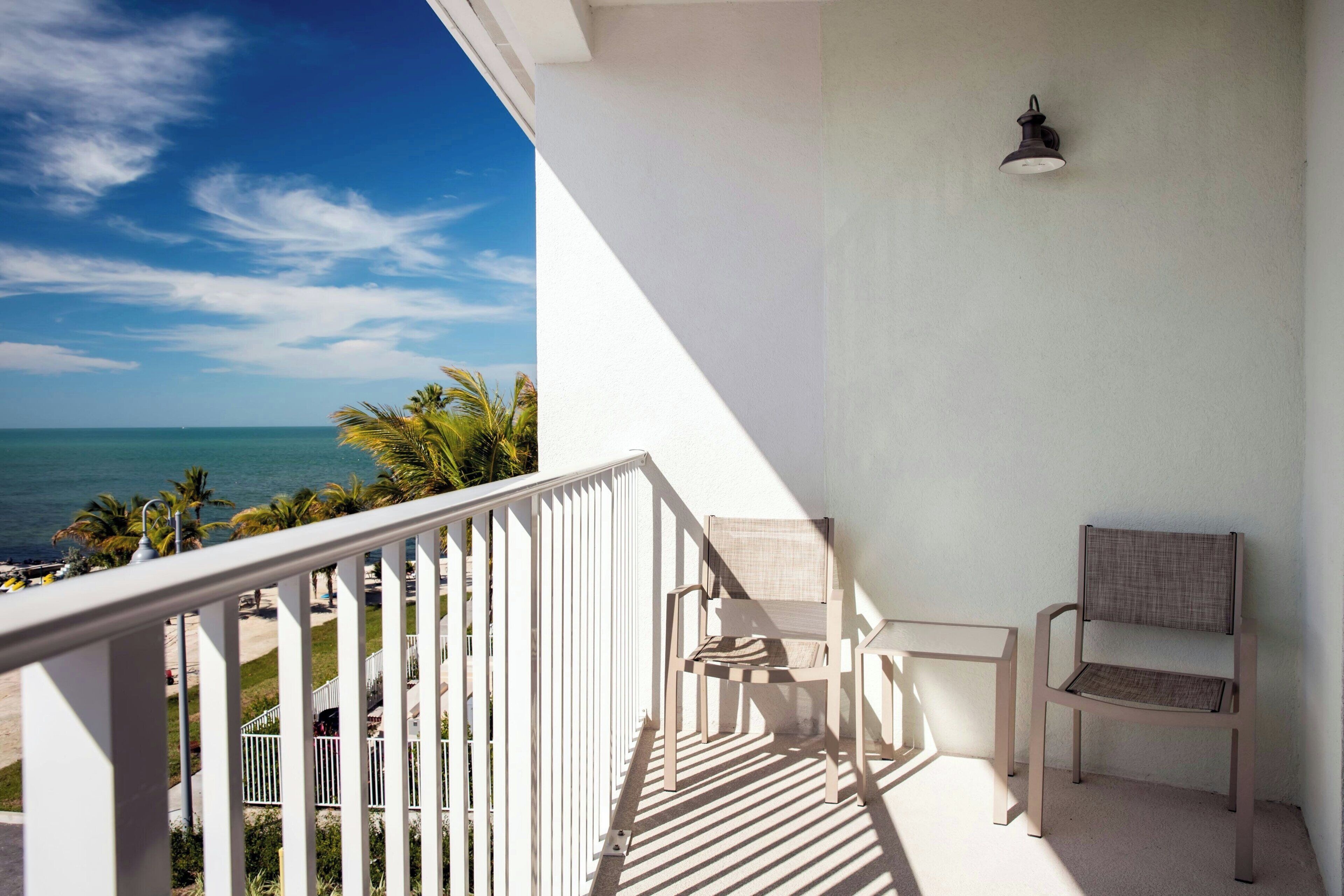 Un balcone con vista sull'oceano, una sedia e un tavolo.