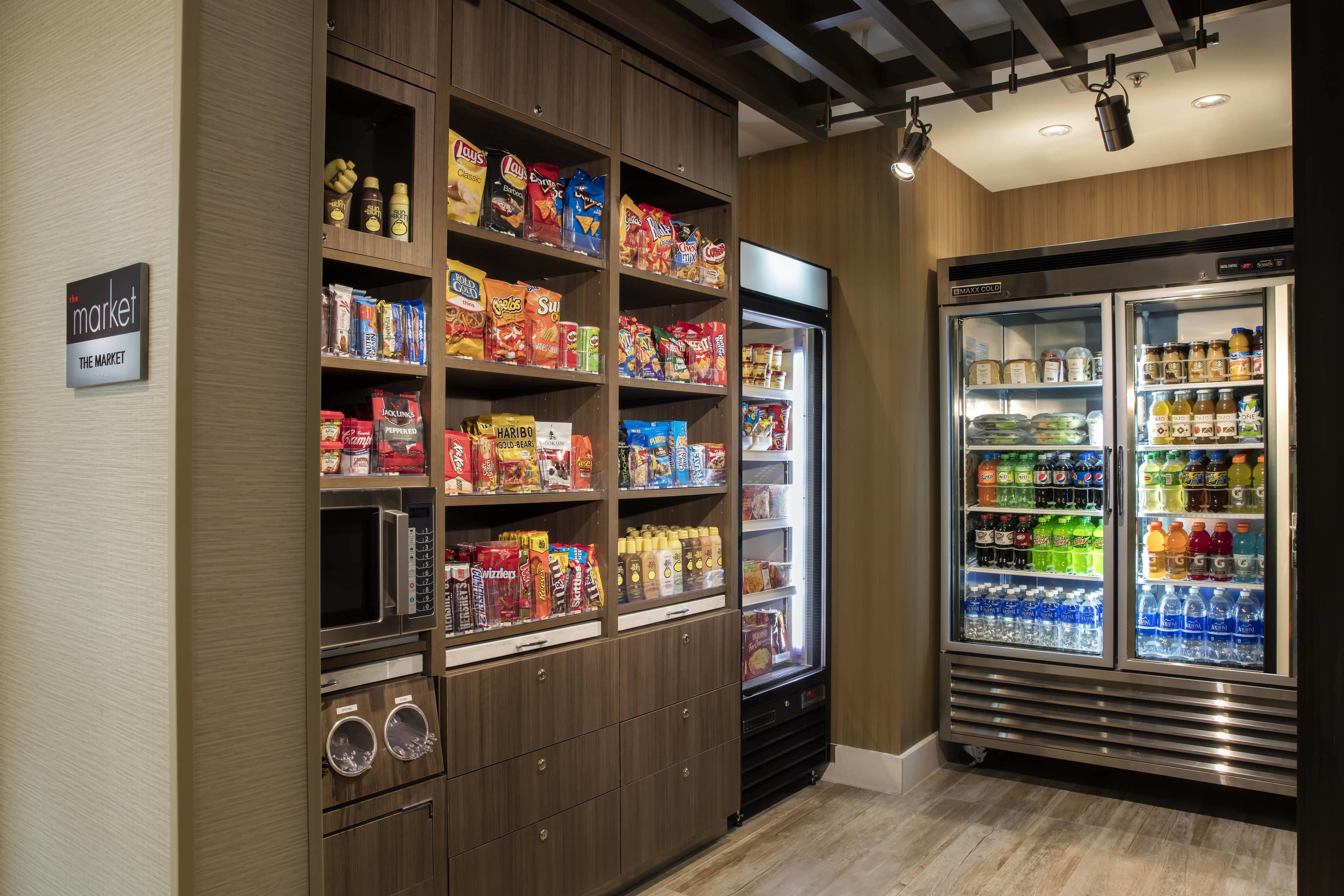 A well-organized snack and beverage area with shelves stocked with various snacks and a refrigerator containing bottled drinks.