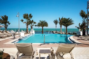 A poolside area with lounge chairs, palm trees, and a view of the sea. - Courtyard by Marriott Faro Blanco Resort, Marathon Florida Keys (Marathon)