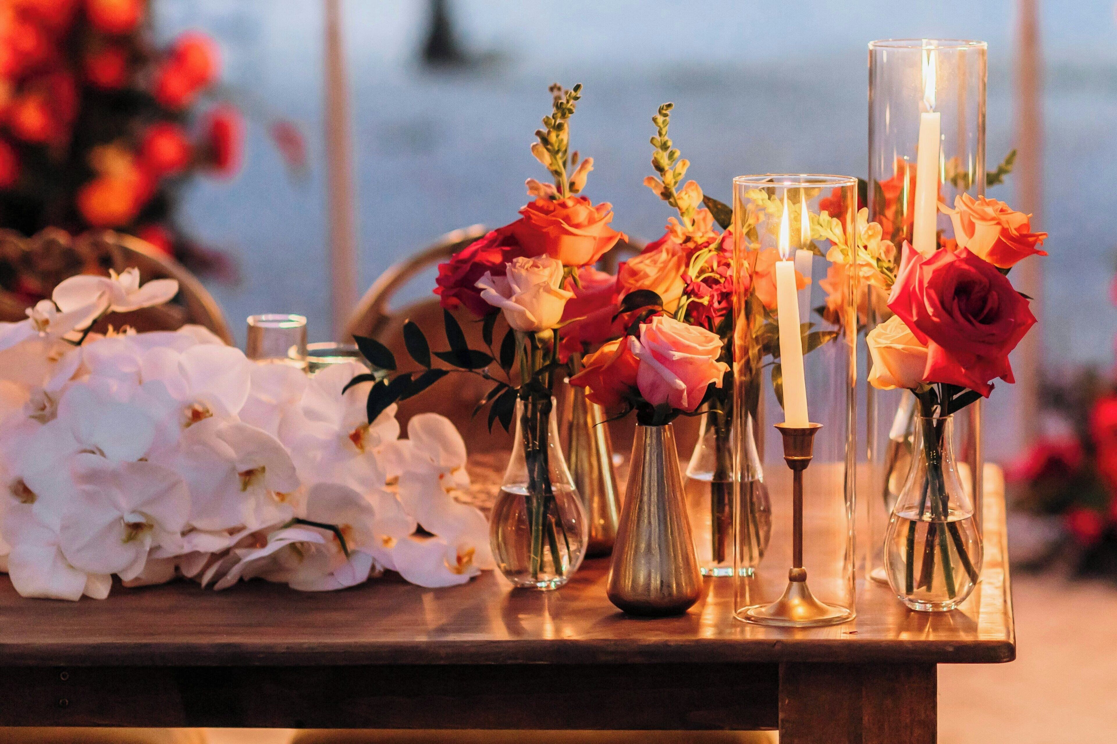 Une table ornée de différents vases contenant des fleurs et des bougies, probablement préparée pour un événement ou une cérémonie spéciale.