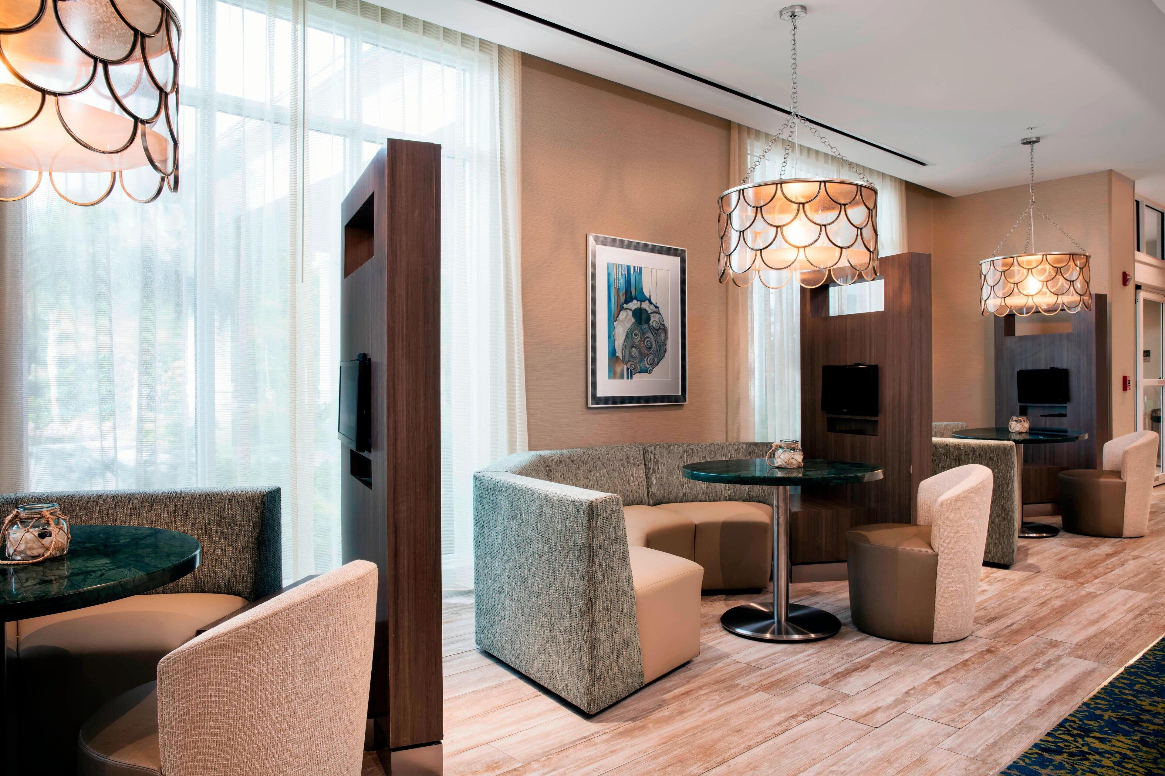 A modern hotel lobby with a curved seating area, a round table, and pendant lighting.