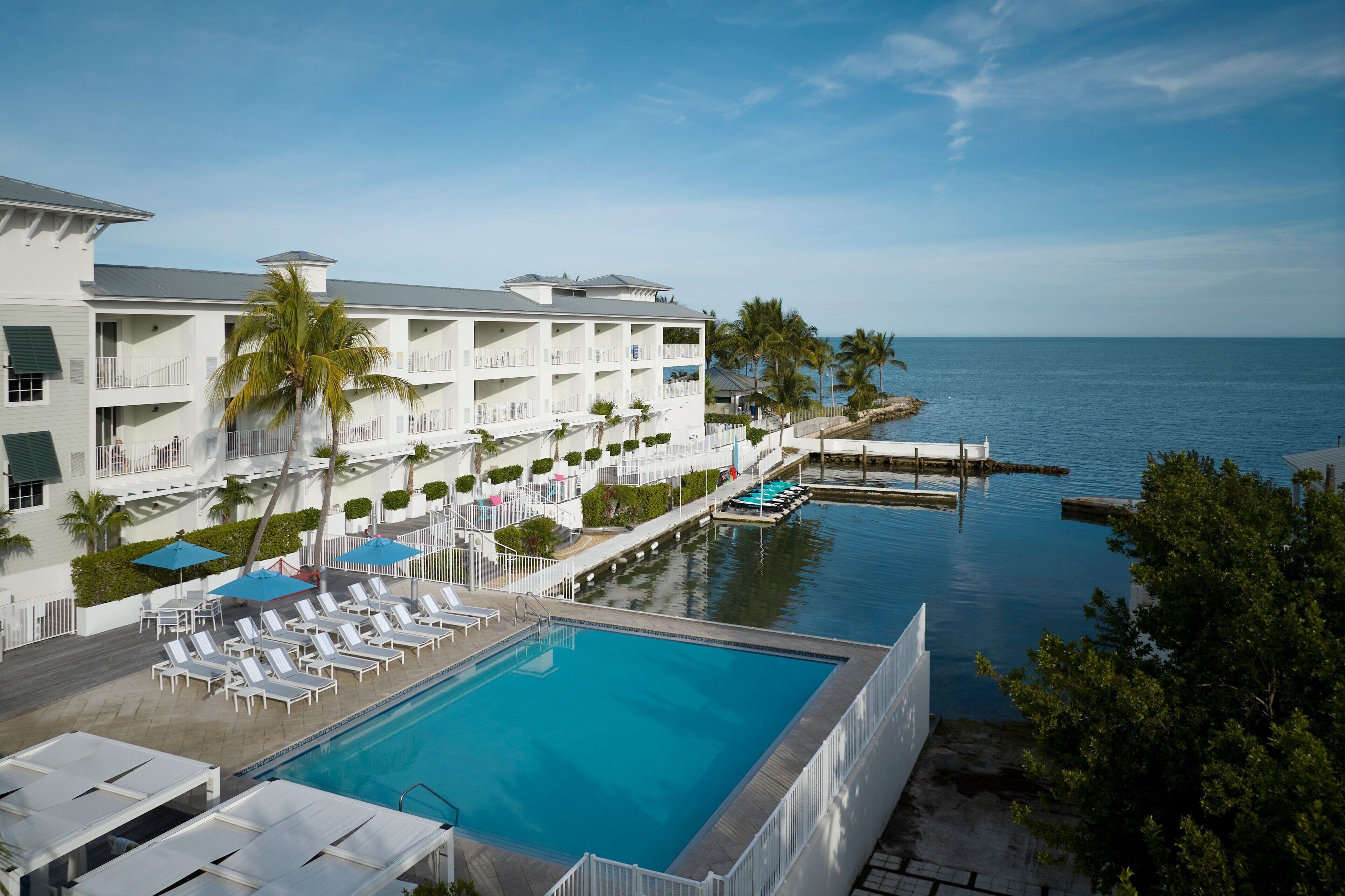 Ett semesterhotell med pool, solstolar och utsikt över havet.