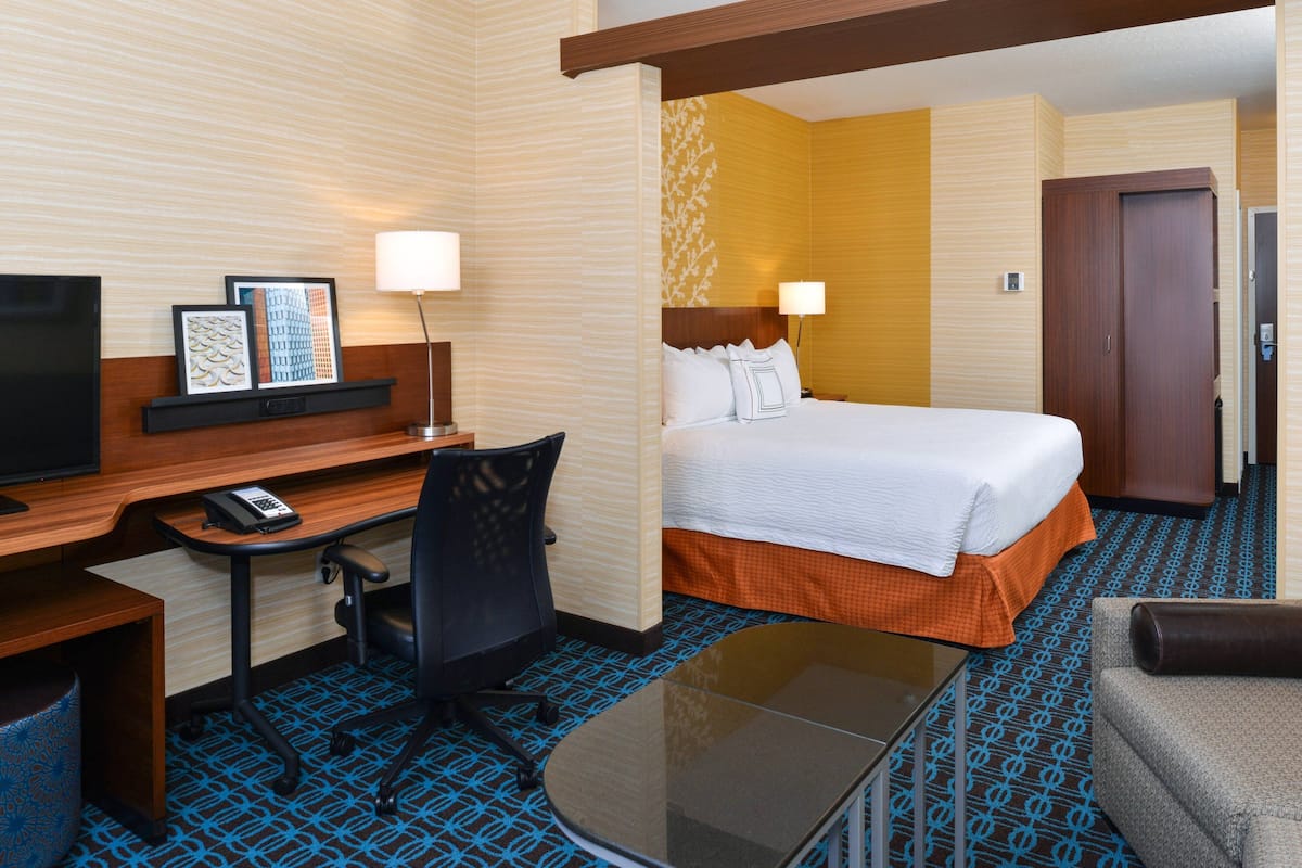 Ein Hotelzimmer mit Bett, Schreibtisch, Stuhl und Fernseher.