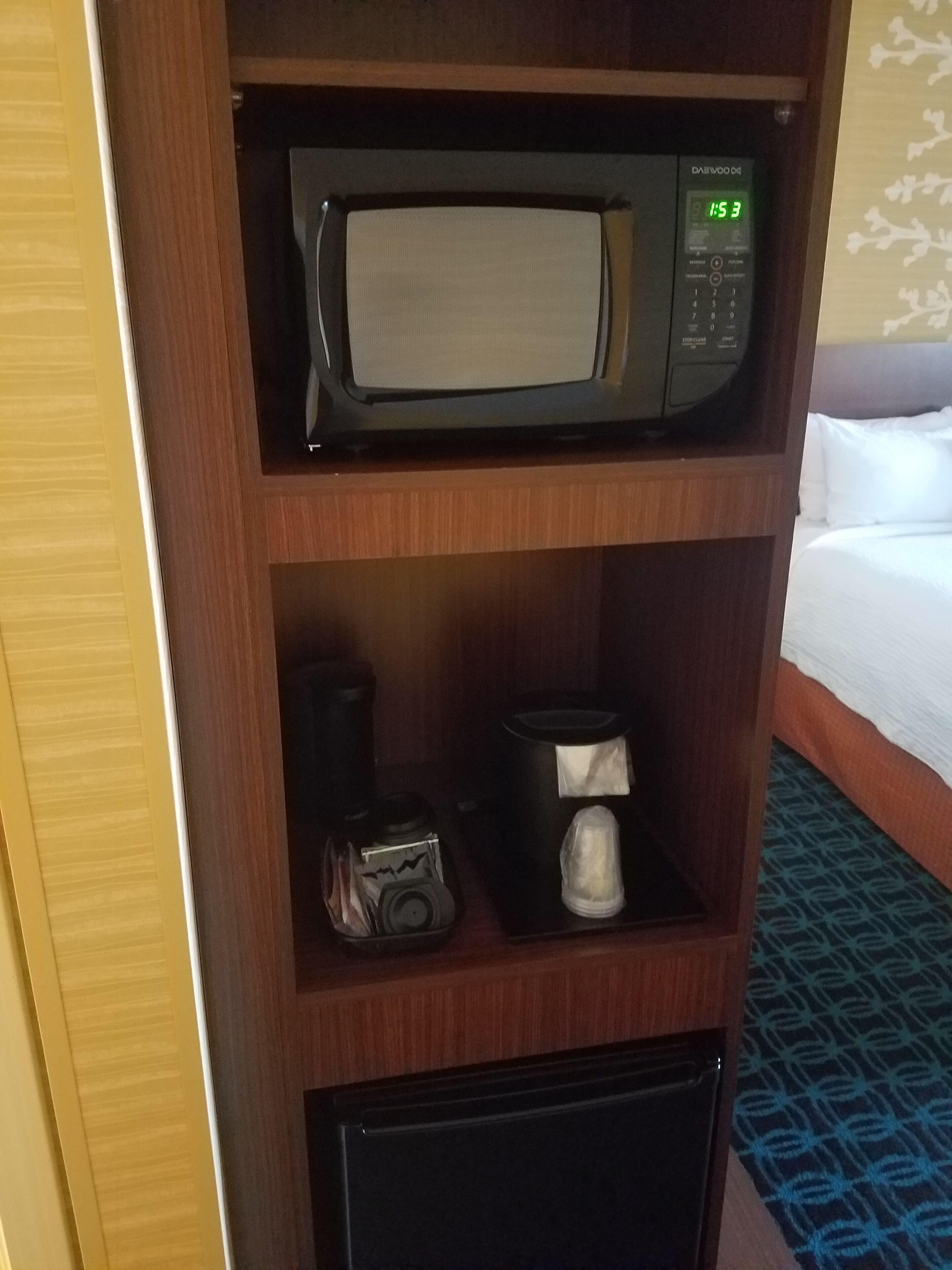 A microwave on a wooden shelf, a coffee maker, and a small appliance below it.