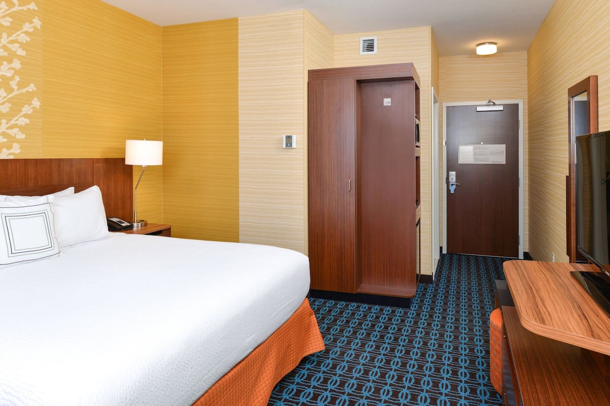 Ein Hotelzimmer mit Bett, Schreibtisch, Fernseher und einer Tür.