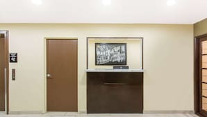 Un espace d’accueil doté d’une porte en bois, d’une pancarte de bienvenue encadrée et d’un petit bureau avec un ordinateur.