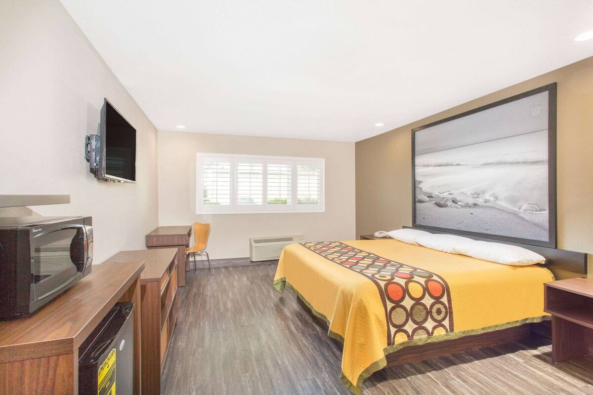 Une chambre d’hôtel équipée d’un lit, d’une télévision, d’un four à micro-ondes et d’un bureau.