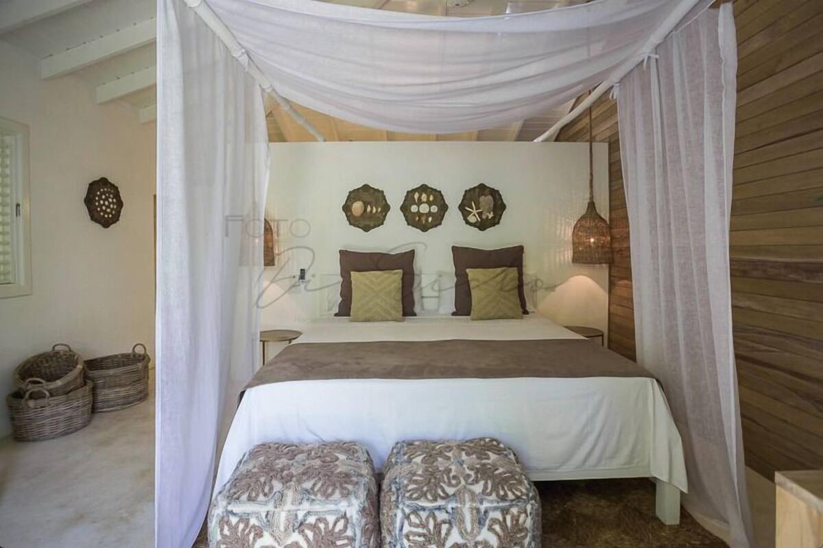 Un dormitorio con cama a dosel, cabecera decorada con placas y lámpara de noche.