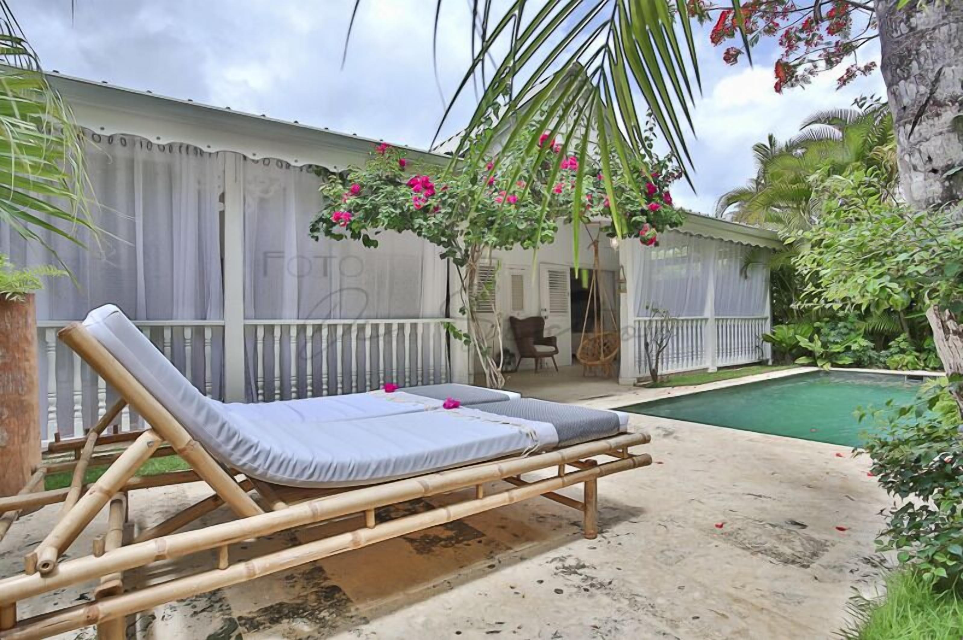 A poolside area with a bamboo lounge chair and a small pool.