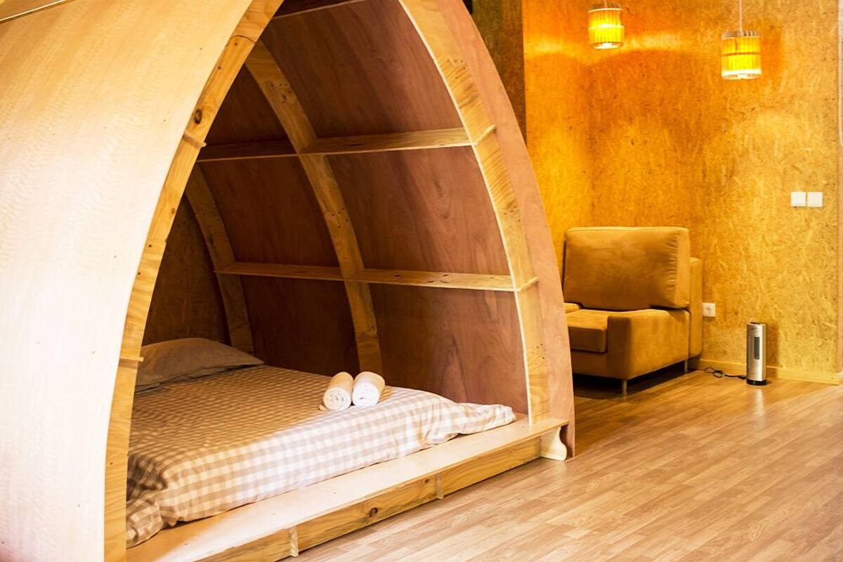 Een gezellige houten kamer met een bed, een stoel en een verwarming.
