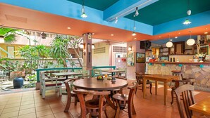A restaurant with wooden tables and chairs, a stone counter, and a view of the outdoors. - Casa Brazil Homestay & Gallery (Karon)