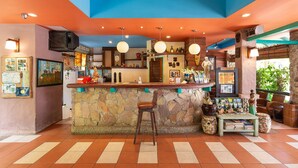 A bar area with a stone counter, stools, and various decorations including a statue and framed pictures. - Casa Brazil Homestay & Gallery (Karon)