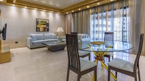 Una sala de estar moderna con una mesa de centro de vidrio, dos sofás y un comedor con una mesa y sillas de vidrio.
