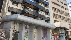 Un moderno edificio de gran altura con varios balcones, amplias ventanas y señalización comercial en la planta baja.