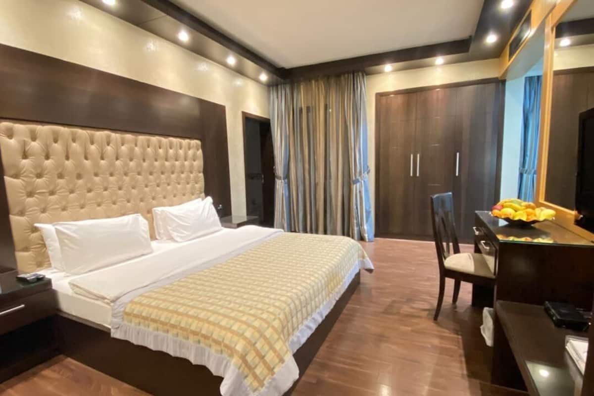 A hotel room with a large bed, a desk with a chair, a TV, and a wardrobe.
