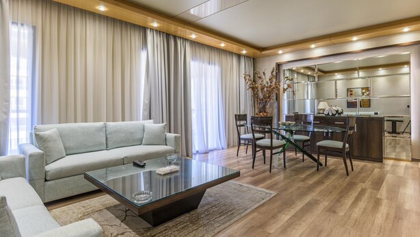 Una sala moderna con un sofá, una mesa de centro de vidrio y un comedor con sillas y una mesa de vidrio.