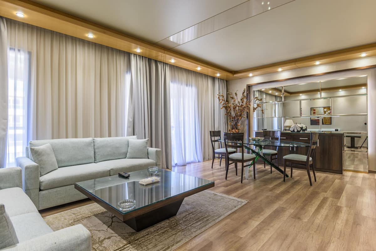 A modern living room with a sofa, a glass coffee table, and a dining area with chairs and a glass table.