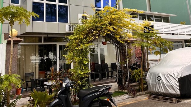 A building with a modern design, featuring large windows and a covered outdoor seating area.